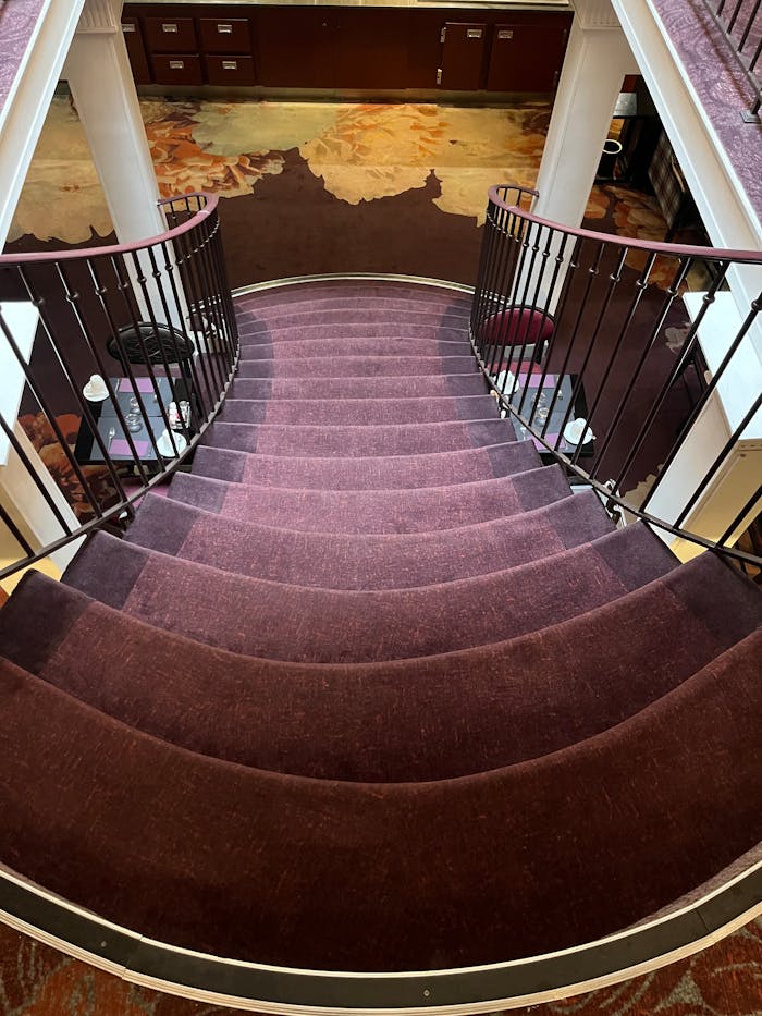 Elegant curved staircase with red carpet and wrought iron railings in a Parisian interior.