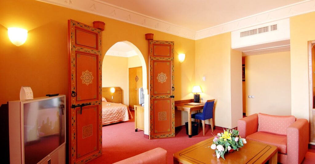 Spacious hotel suite with colorful decor and modern furnishings, offering a warm and inviting atmosphere.