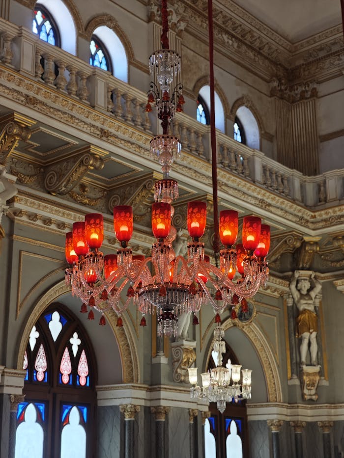 Opulent ballroom interior featuring a red and clear glass chandelier with intricate details.